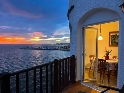 a balcony with a view of the ocean at sunset at Apartamento en acantilado con wifi y aire acondicionado in Sitges