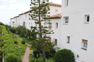 a large white building with a tree next to it at Apartamento en acantilado con wifi y aire acondicionado in Sitges