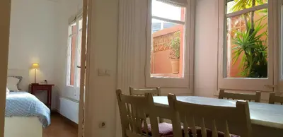 a dining room with a table and a bed and windows at Filmoteca Sarria 1- wifi quiet bright comfi in Barcelona