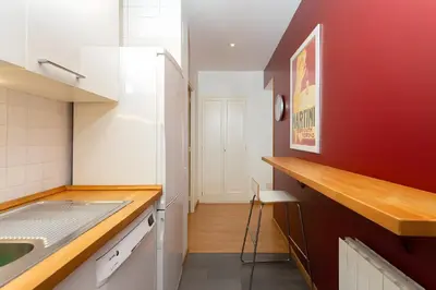 a kitchen with a sink and a red wall at Filmoteca Sarria 1- wifi quiet bright comfi in Barcelona