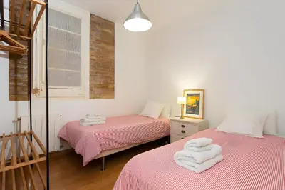 two beds in a room with pink sheets and white towels at Filmoteca Sarria 1- wifi quiet bright comfi in Barcelona