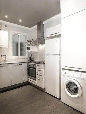a white kitchen with a washing machine and a washer at Mai & Maud Paralel Apartment in Barcelona