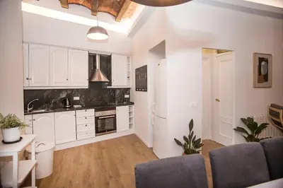 a kitchen with white cabinets and a table and chairs at Mai & Maud Ronda Apartment in Barcelona