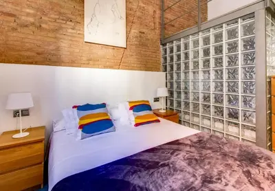 a bedroom with a large bed and a brick wall at Camp Nou Apartment in Hospitalet de Llobregat