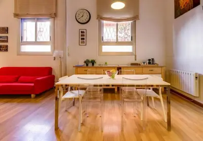 a living room with a table and a red couch at Camp Nou Apartment in Hospitalet de Llobregat