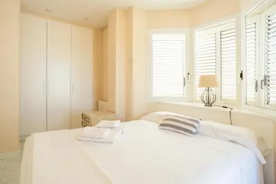 a white bedroom with a large white bed and windows at Casa Cala Balmins in Sitges