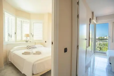 a white bedroom with a bed and a window at Casa Cala Balmins in Sitges