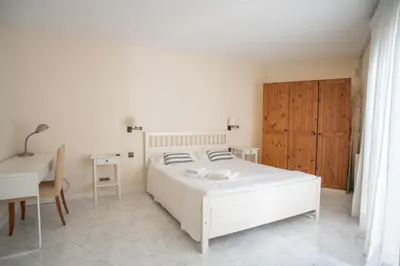 a white bedroom with a white bed and a desk at Casa Cala Balmins in Sitges