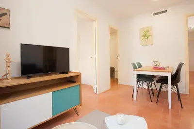 a living room with a television and a table with chairs at Click&Flat Europa Fira Apartments in Hospitalet de Llobregat