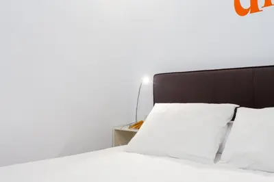 a bed with white sheets and a black headboard at Casa Cosi Sant Antoni in Barcelona