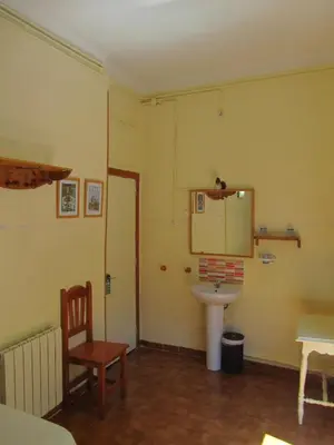 a bathroom with a sink and a table and a chair at Pension Alamar in Barcelona