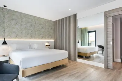 a bedroom with a large white bed and a desk and chair at Niu Barcelona Hotel in Barcelona