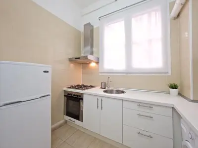 a white kitchen with a sink and a refrigerator at Suites4days Gaudi Eixample in Barcelona