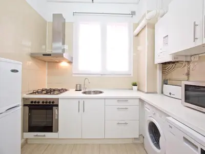a kitchen with white cabinets and a sink and a window at Suites4days Gaudi Eixample in Barcelona