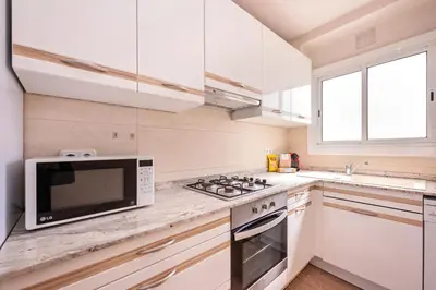 a white kitchen with a microwave and a stove at Sweett - Atic Eloi in Barcelona