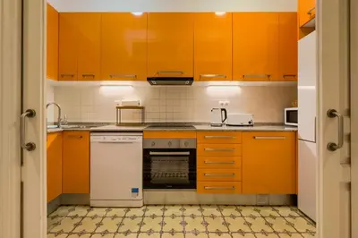 a kitchen with orange cabinets and a white dishwasher at Novus Homes Barcelona Eixample in Barcelona