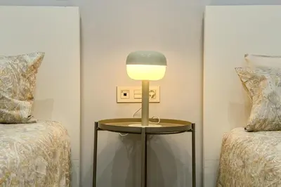 a lamp on a table next to two beds at Novus Homes Barcelona Eixample in Barcelona