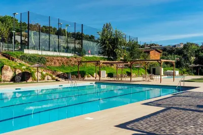 a swimming pool with blue water in a park at Camping El Pasqualet in Caldes de Montbui