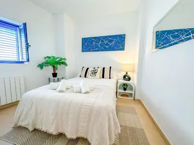 a white bedroom with a bed with towels on it at Sanctuary Penthouse by Hello Homes Sitges in Sitges