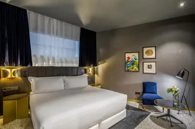 a bedroom with a white bed and a blue chair at Room Mate Collection Gerard, Barcelona in Barcelona