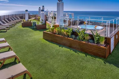 a deck with a hot tub and benches and the ocean at GHT Maritim in Calella