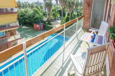 a balcony with two chairs and a swimming pool at HomeHolidaysRentals Amaral in Pineda de Mar