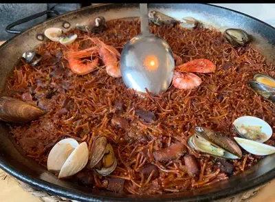 a pan of food with shrimp and mussels and a spoon at Apartment Foix in Cubelles