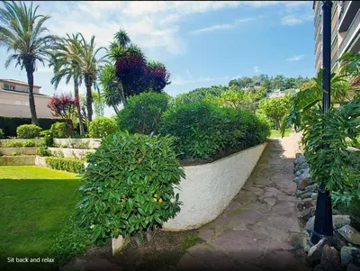 a large stone planter with bushes and palm trees at The Hollidays Apartment in Calella