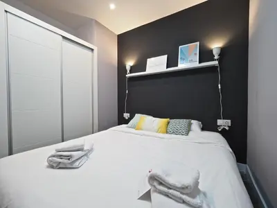 a bedroom with a large white bed with a black wall at Torrassa Cozy Apartment by Olala Homes in Hospitalet de Llobregat