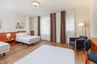 a hotel room with two beds and a chair at Sercotel Arrahona Sabadell in Sabadell