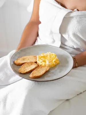 a woman holding a plate with eggs and toast at Aparthotel Solifemar in Castelldefels