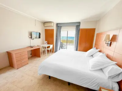 a bedroom with a large white bed and a desk at Aparthotel Solifemar in Castelldefels