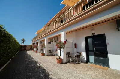a building with a black door and some chairs and plants at Aparthotel Solifemar in Castelldefels