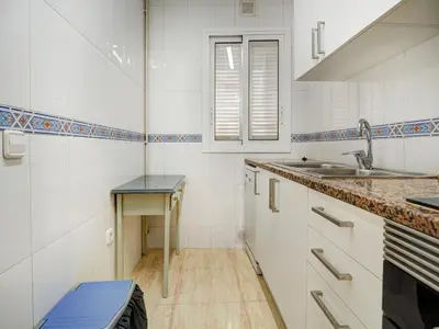 a kitchen with white cabinets and a sink and a table at Parellades Apartment by Hello Homes Sitges in Sitges