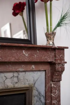 a mirror and a vase with flowers on a fireplace at CasaNova Guest House in Barcelona