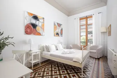 a white bedroom with a bed and a chair at CasaNova Guest House in Barcelona