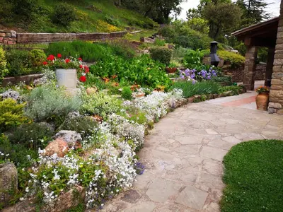 a garden with colorful flowers and a stone walkway at Entre Roures in Moià