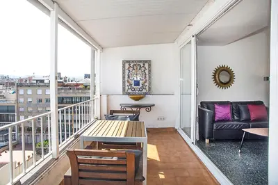a living room with a couch and a table on a balcony at The Gran Via Penthouse in Barcelona