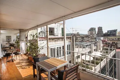 a balcony with a table and chairs and a view of a city at The Gran Via Penthouse in Barcelona
