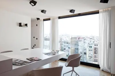 a white dining room with a large window at DestinationBCN Urgell Apartment in Barcelona
