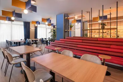 a restaurant with tables and a red bench at B&B HOTEL Barcelona Rubí in Rubí