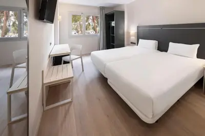 a bedroom with a large white bed and a table at B&B HOTEL Barcelona Rubí in Rubí