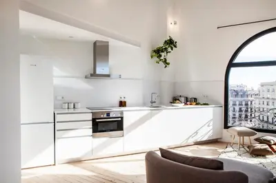 a kitchen with white cabinets and a large window at DestinationBCN Marimon Apartment in Barcelona