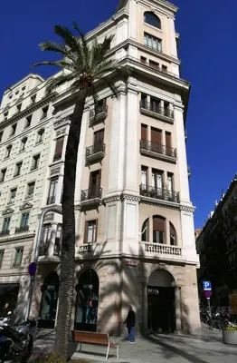 a tall white building with a palm tree in front of it at DestinationBCN Marimon Apartment in Barcelona