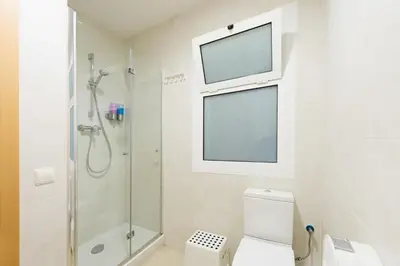 a bathroom with a shower and a toilet with a window at Hostal BESTPRICE Barcelona Stadium in Barcelona