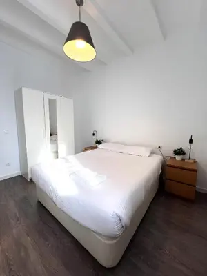 a bedroom with a large white bed and a lamp at Camp Nou Apartment in Hospitalet de Llobregat