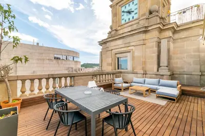 a balcony with a table and chairs and a clock tower at Unique Rentals - Placa Catalunya Central Apartments in Barcelona
