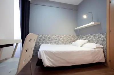 a bedroom with a white bed and a chair at Hostal Nitzs Bcn in Barcelona