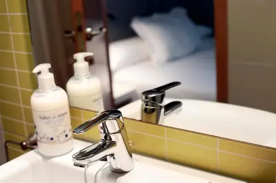 a bathroom sink with a bottle of soap and a mirror at Hostal Nitzs Bcn in Barcelona