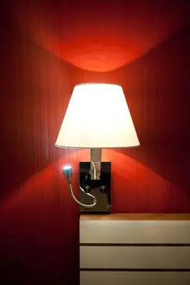 a lamp on top of a dresser with a red wall at Hostal Bcn 46 in Barcelona